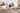 Dans une chambre à coucher aménagée dans le style Japandi, il y a un lit. Différents coussins y sont posés, dont certains représentent des photos de personnes en noir et blanc. D’autres coussins ont été créés soi-même avec un fond rose et des cliparts de texte.